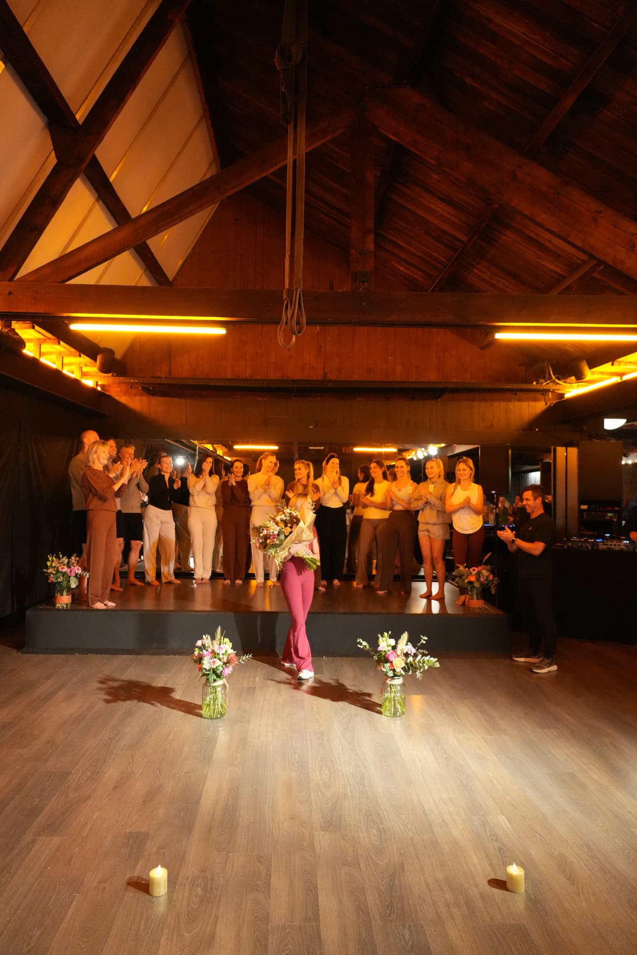 Overzicht van het team op het podium met een vrouw en haar boeket tussen bloemen en kaarsen