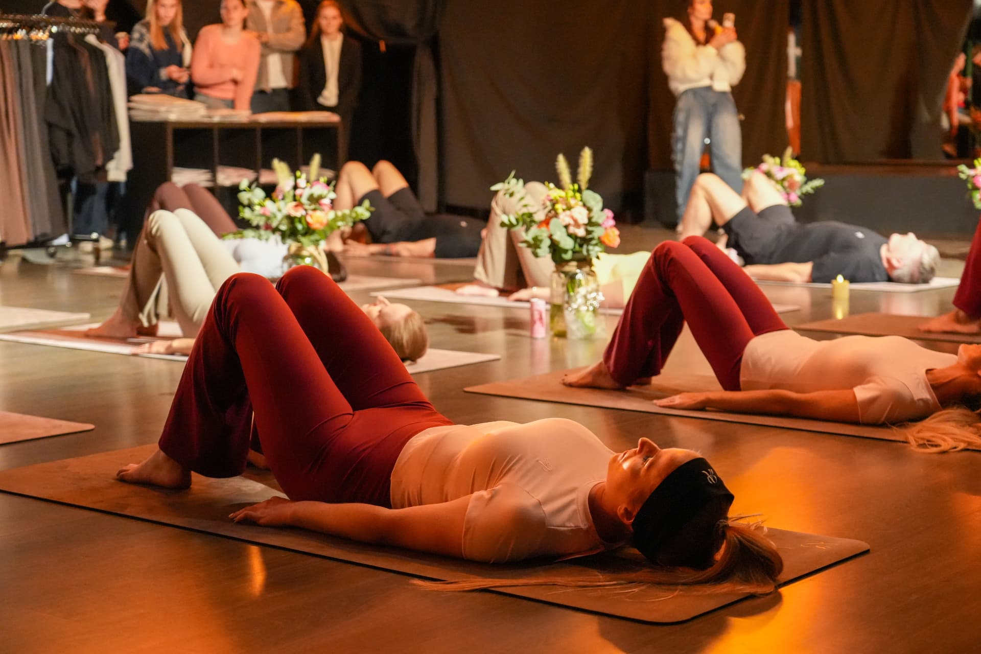 Een deelnemer in bordeauxrode broek ligt op een mat tijdens de sessie