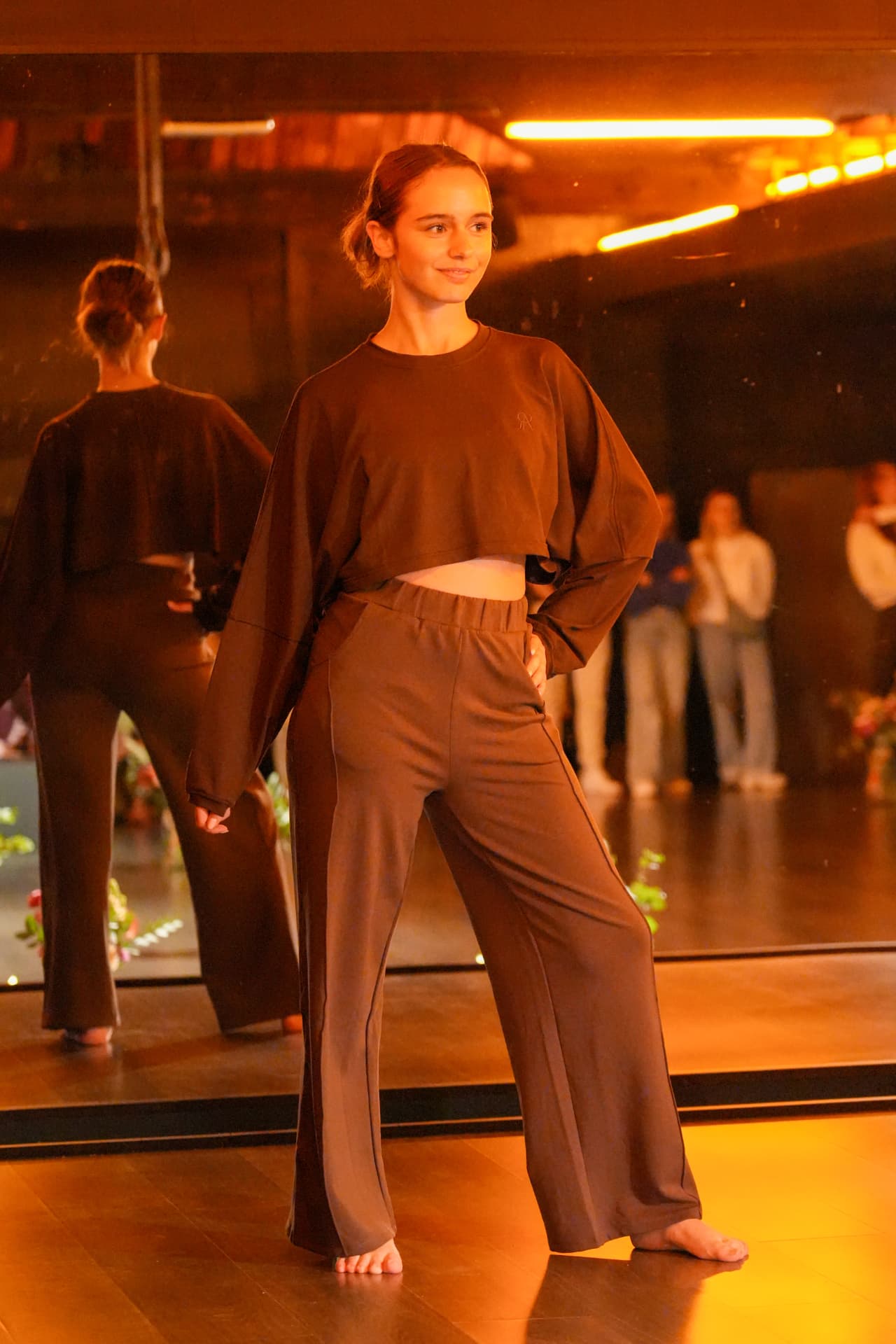 Een model toont een bruine korte sweater en wijde broek voor de spiegelwand