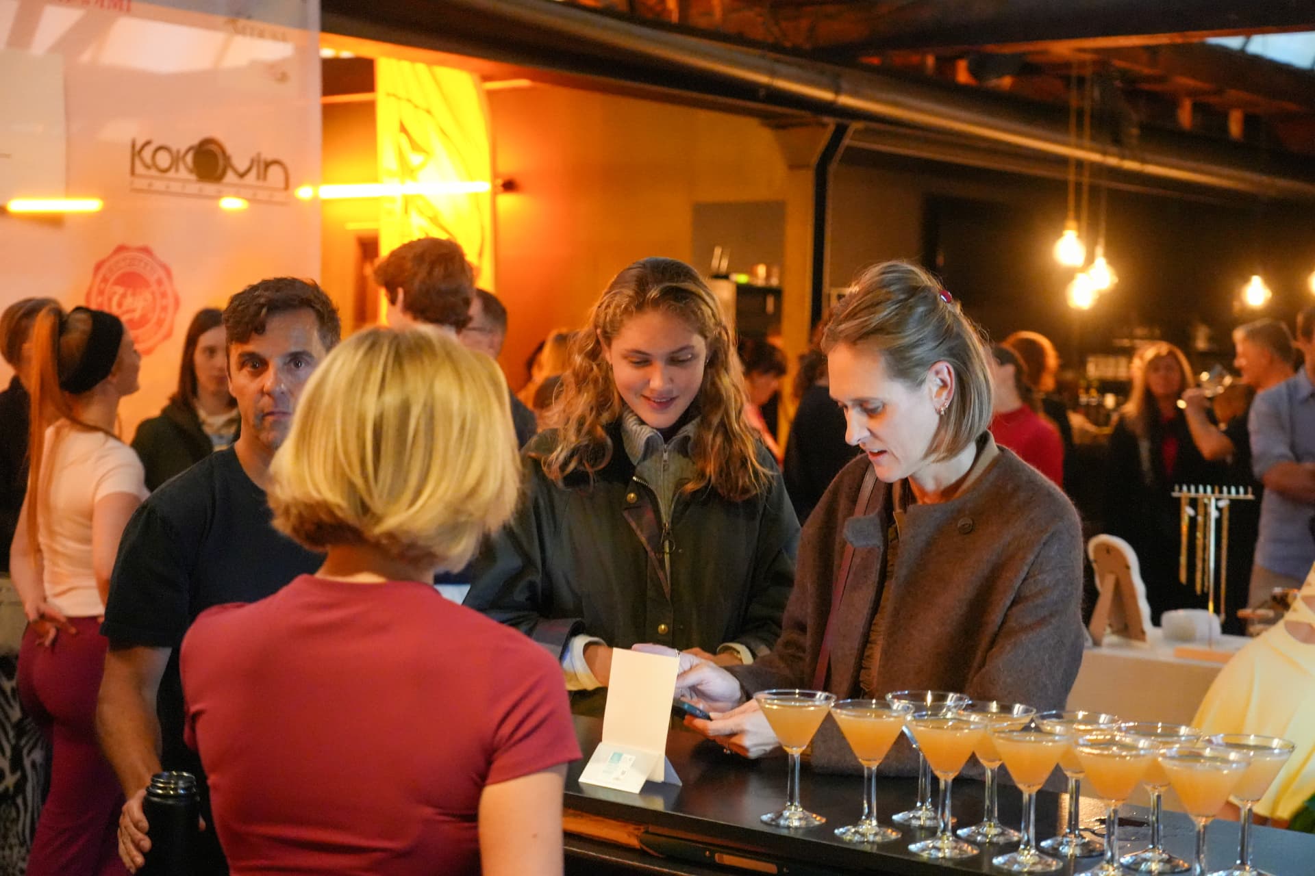 Bezoekers bij de ontvangstbalie met rijen cocktailglazen