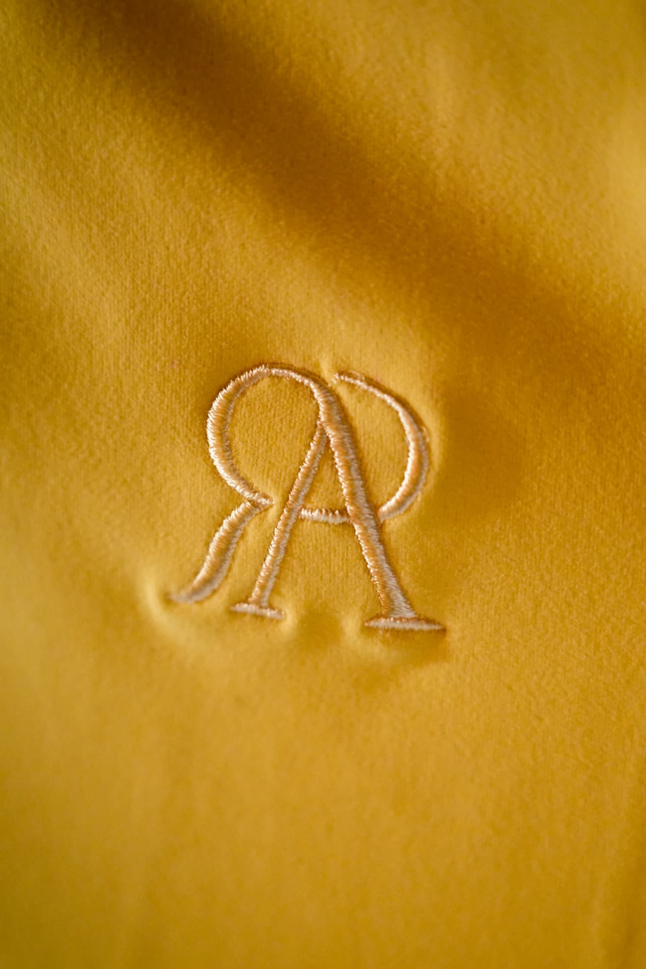 Het RA-logo geborduurd op gele stof