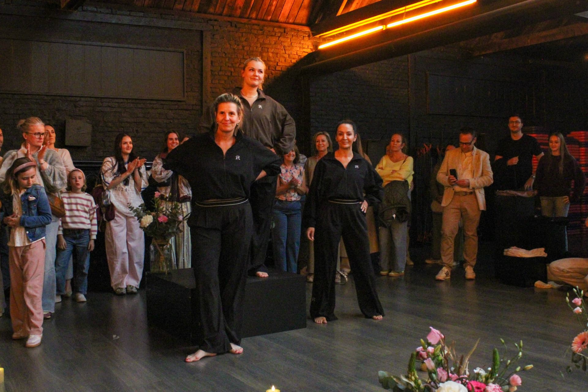 Modellen in donkere trainingspakken poseren voor het publiek