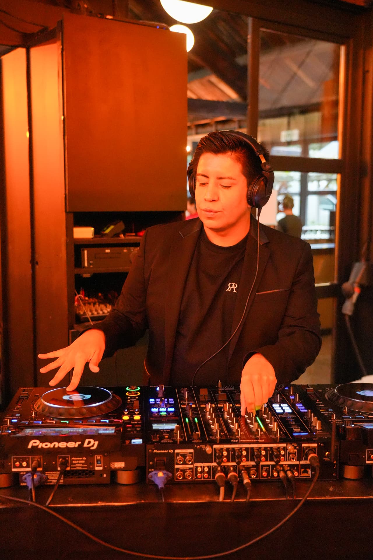 Een dj met hoofdtelefoon staat achter het mengpaneel