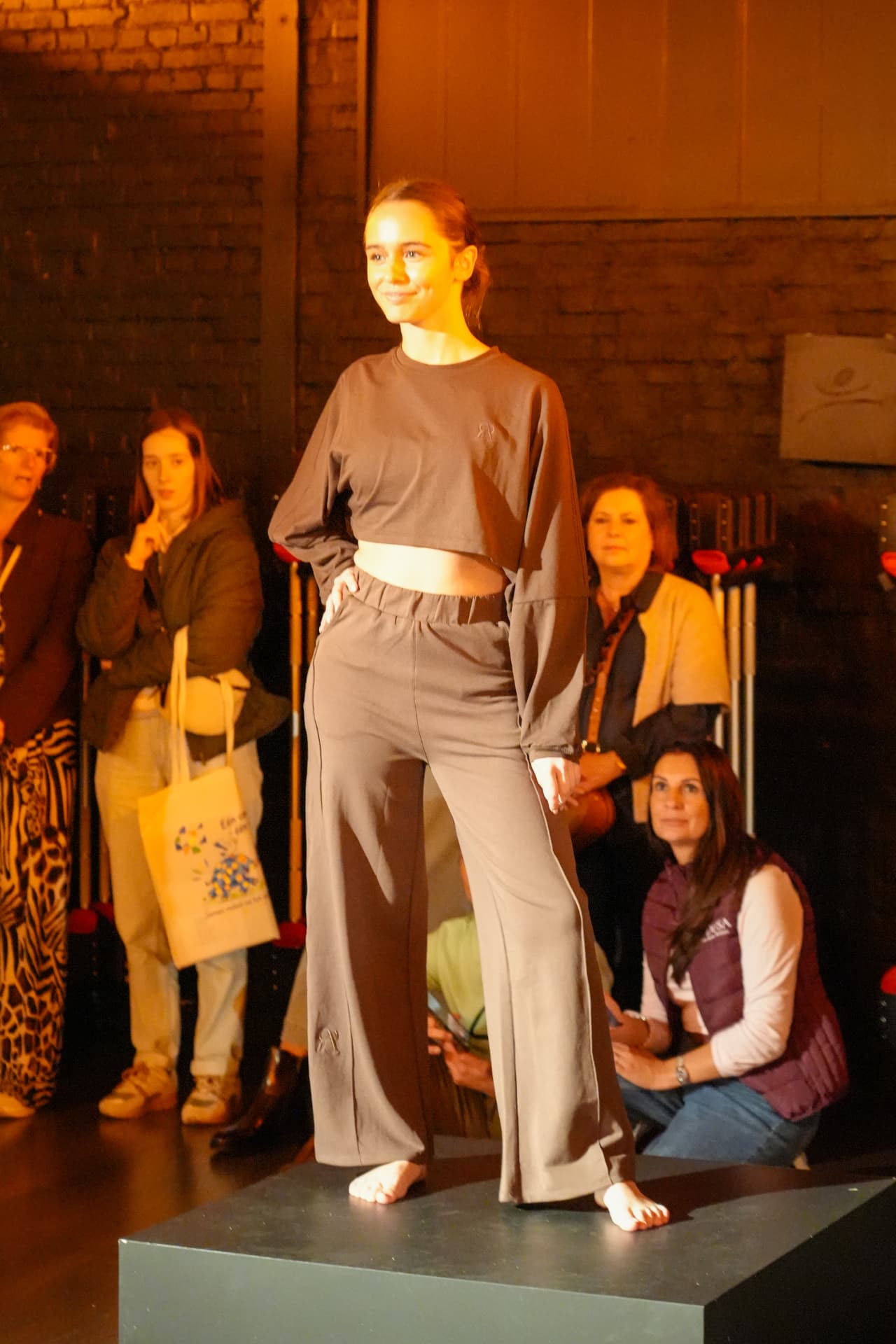 Een model poseert in een taupekleurige korte sweater en wijde broek