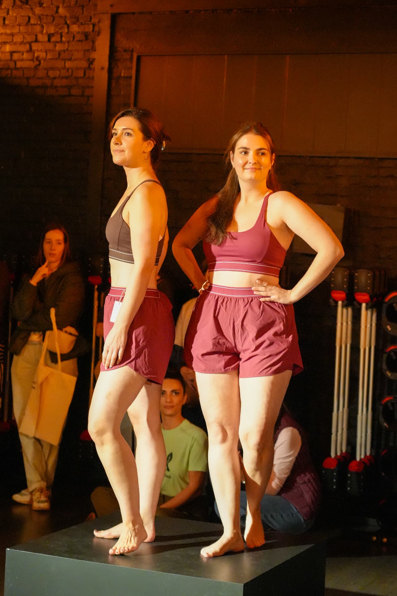 Twee modellen poseren samen in sporttops en bordeauxrode shorts