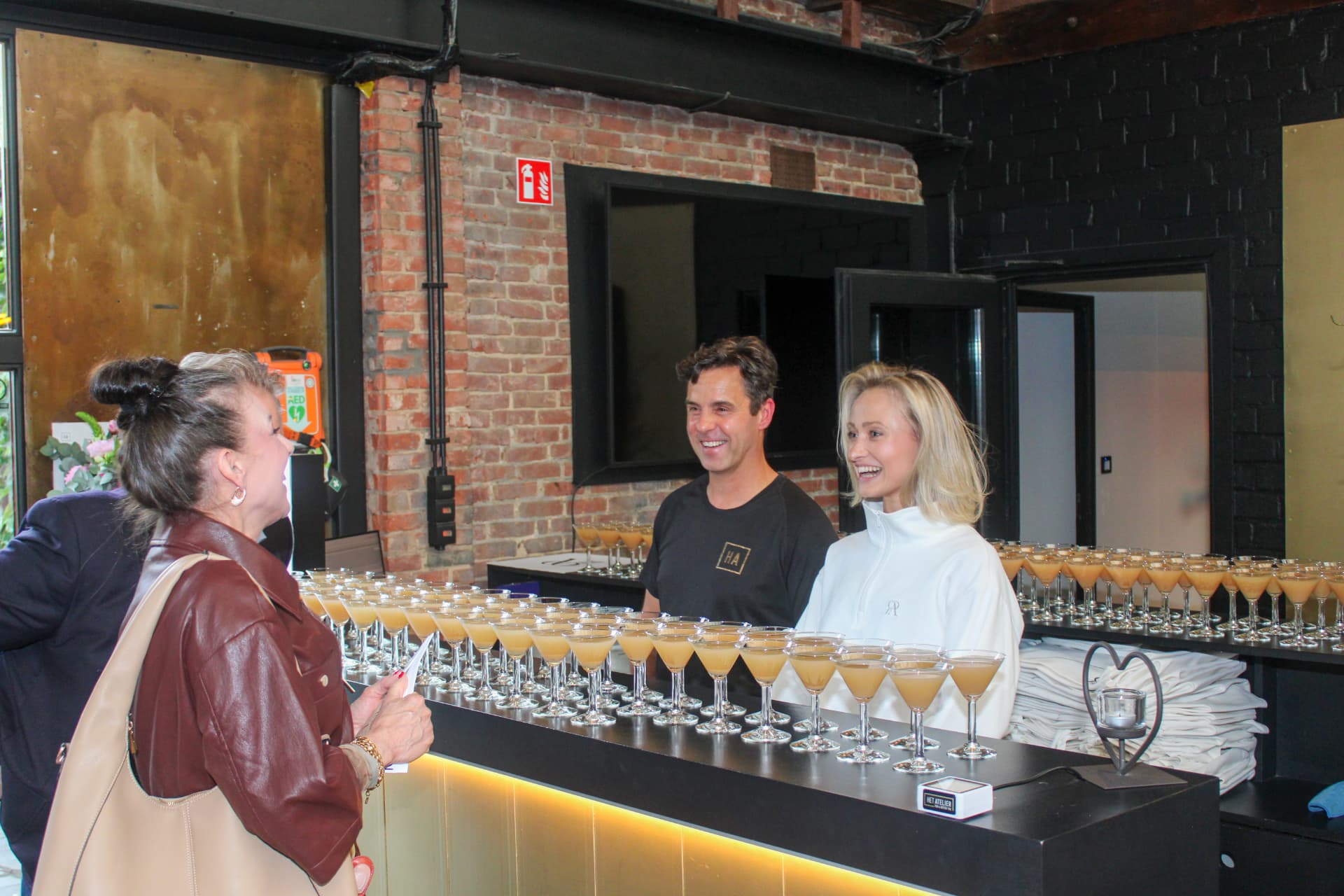 Het barteam lacht naar een gast achter de bar