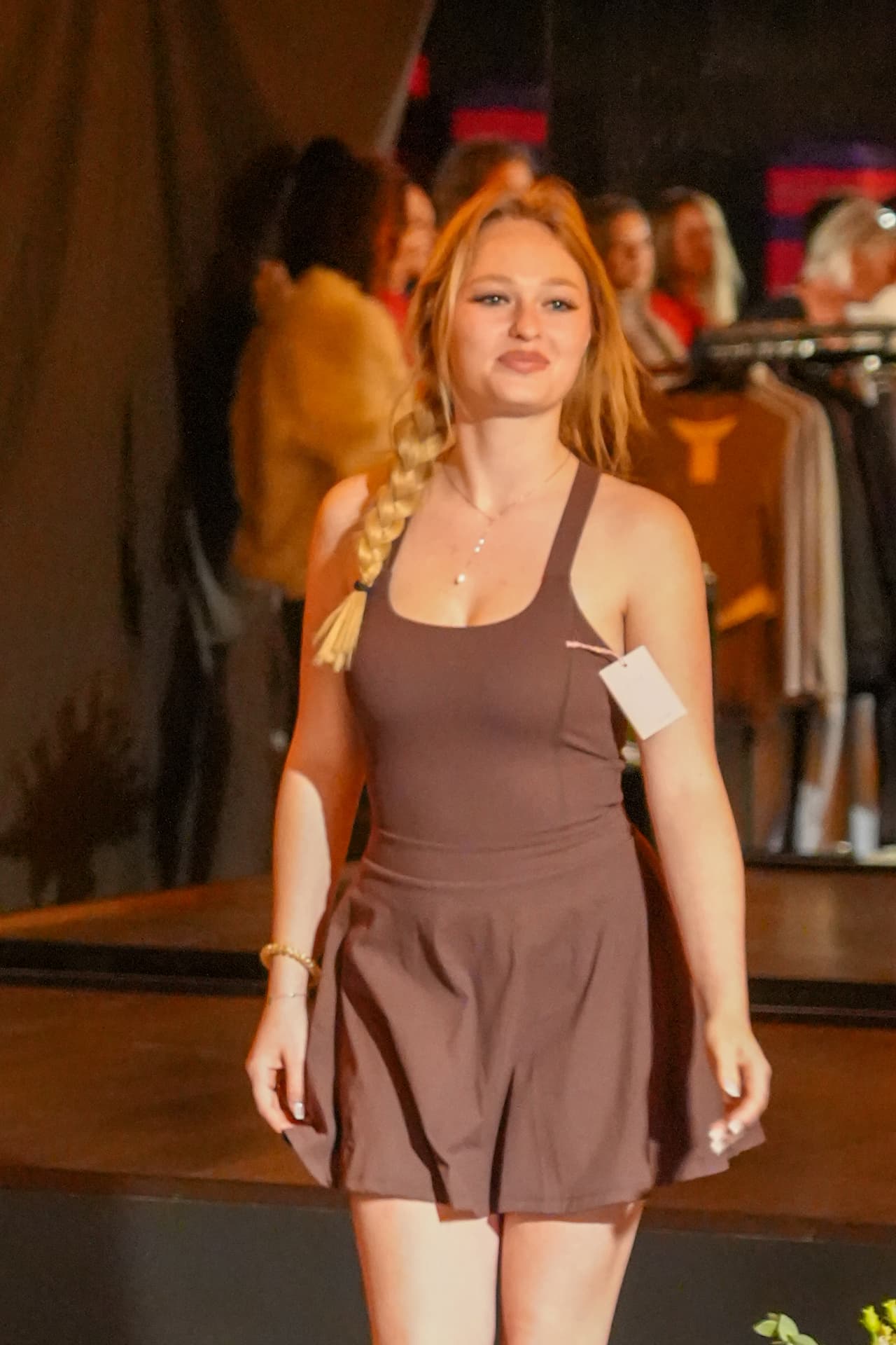 Een model met een vlecht toont een bruine sportjurk