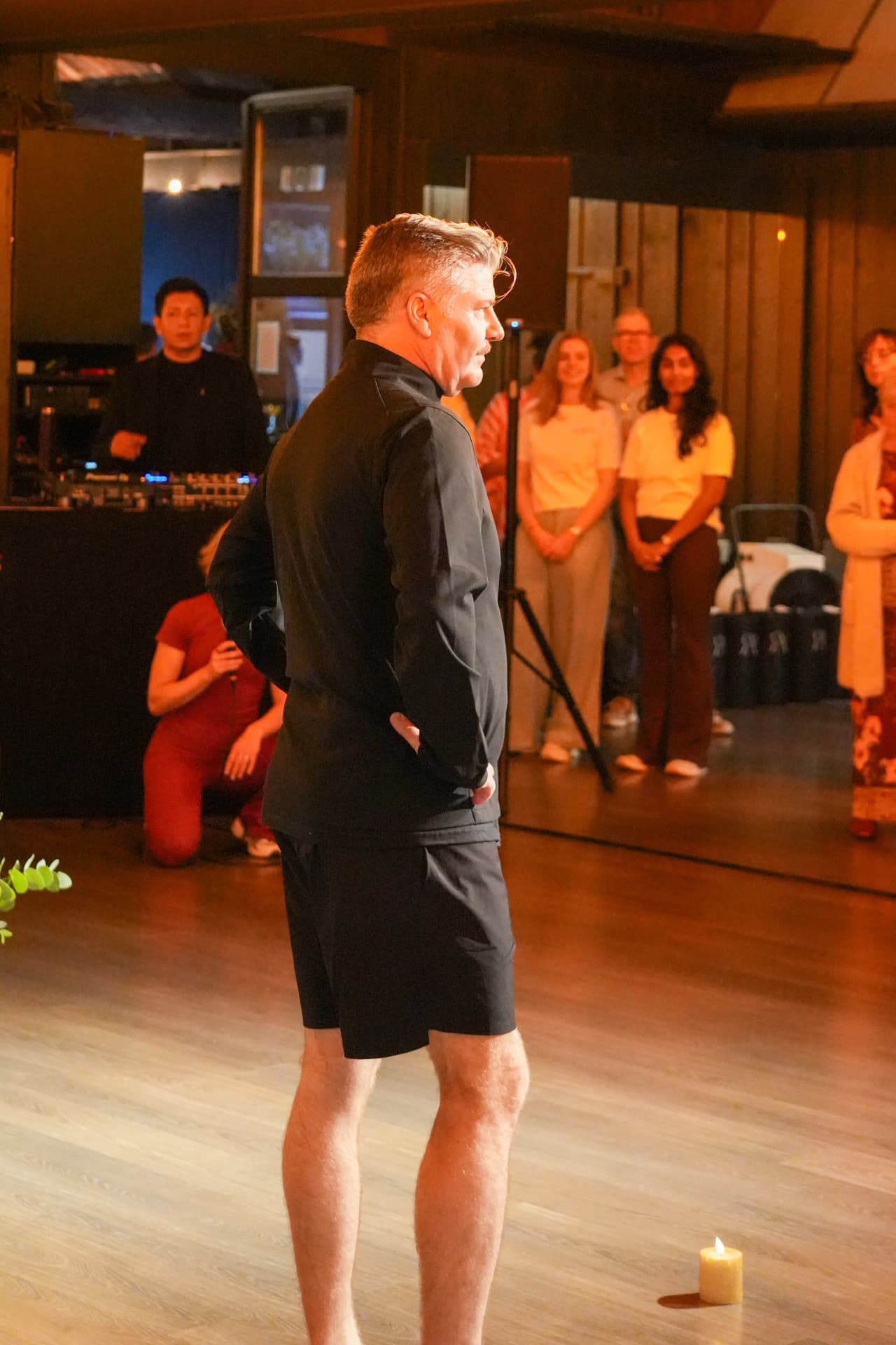 Een model toont een zwart sportjasje en zwarte short van opzij