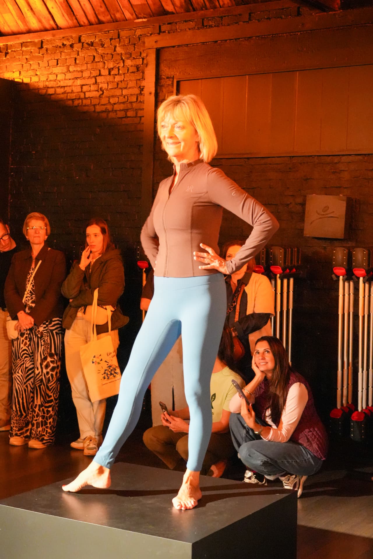 Een model poseert in een bruin sportjasje en blauwe legging