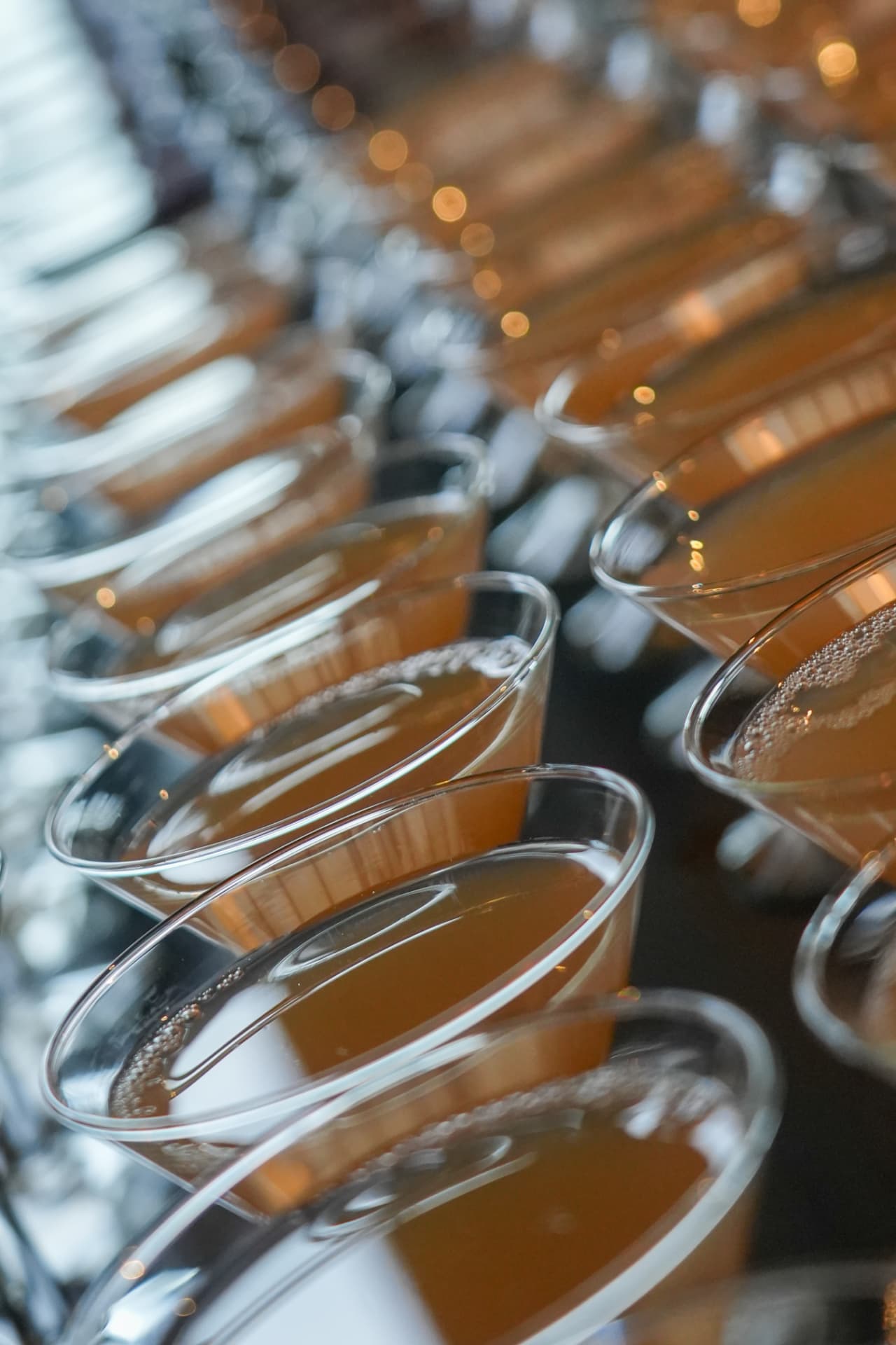Rijen cocktailglazen met een oranjebruin drankje, klaar voor de gasten