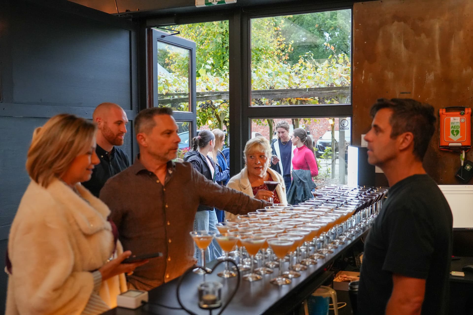 Bezoekers nemen een drankje aan de bar met rijen cocktailglazen