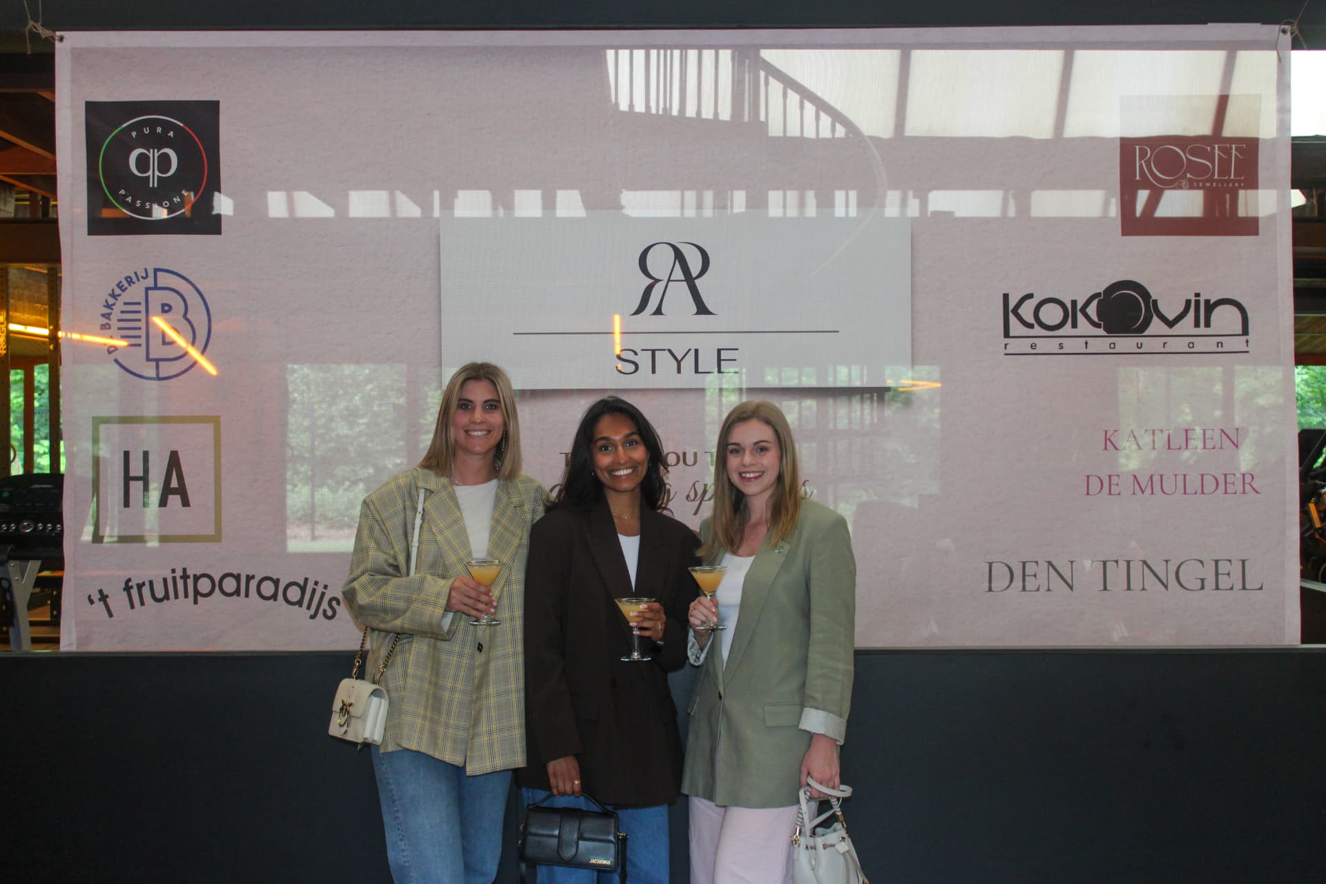 Drie bezoekers met een drankje voor het sponsordoek