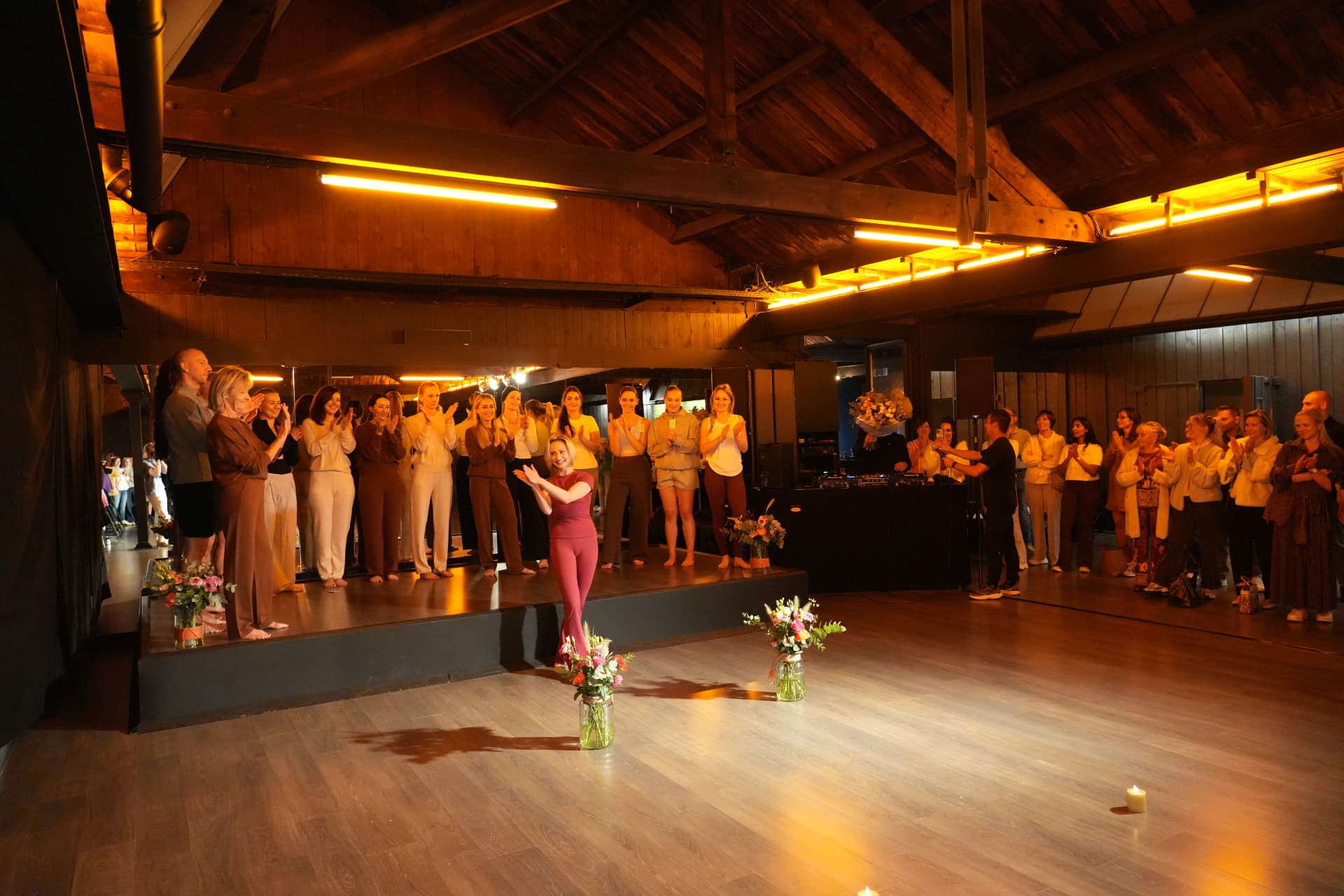 Het team en de bezoekers applaudisseren voor een vrouw in een bordeauxrode outfit