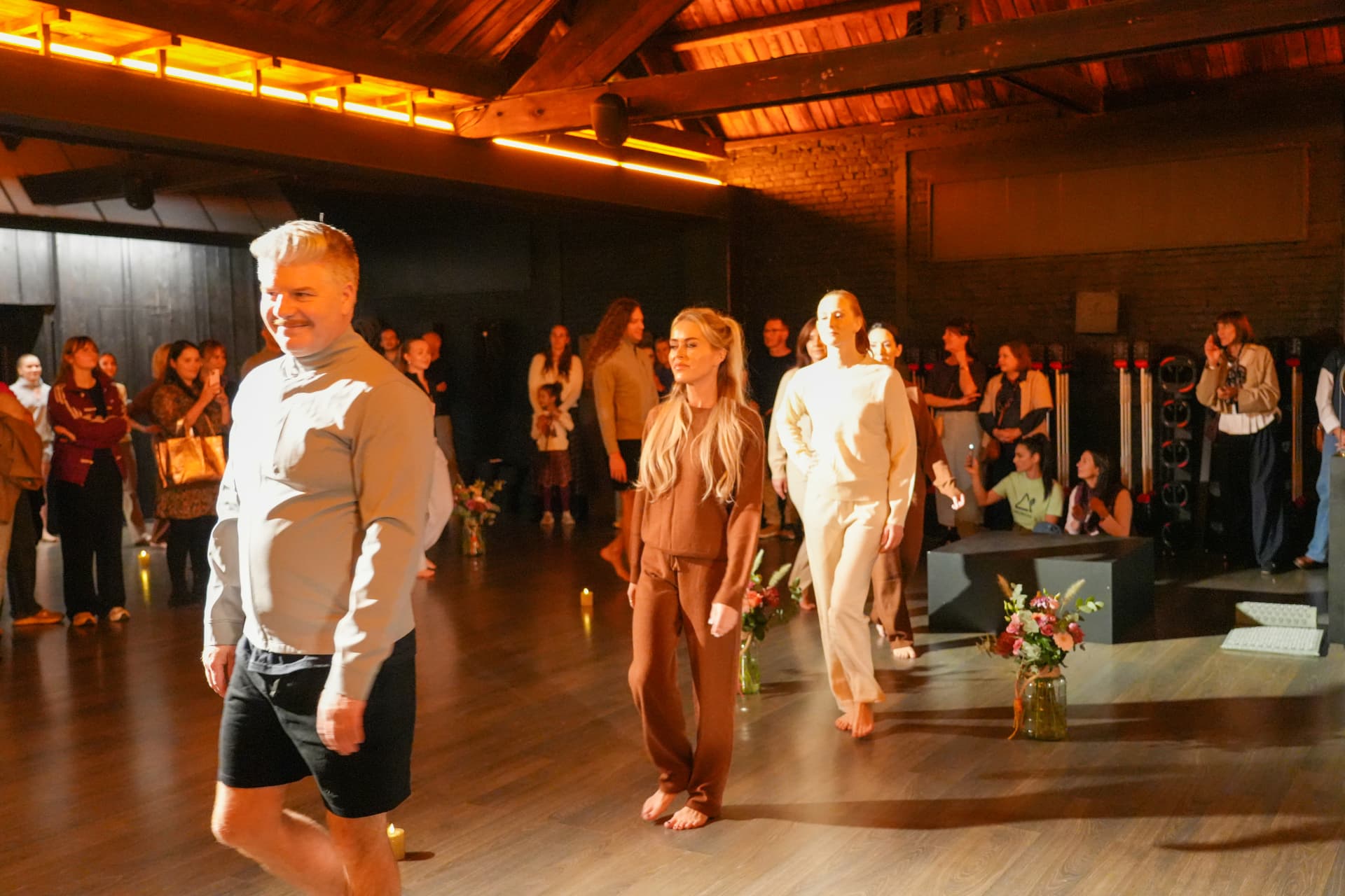 Modellen in sportkleding wandelen achter elkaar langs bloemen en kaarsen