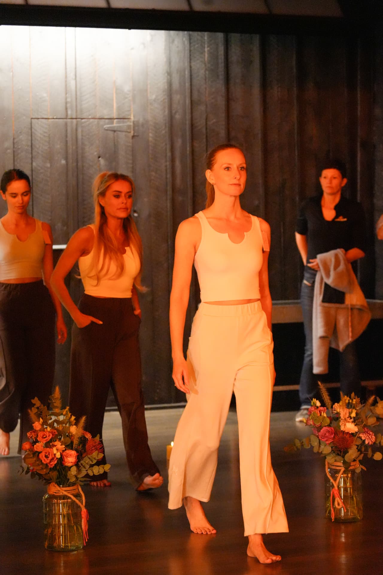 Een model in een witte korte top en wijde witte broek wandelt langs de bloemen